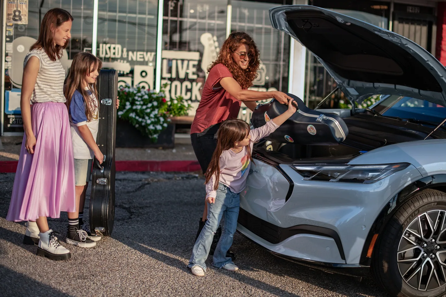 A family loading up the frunk (front trunk) of the 2024 Mustang Mach-E at a charging station