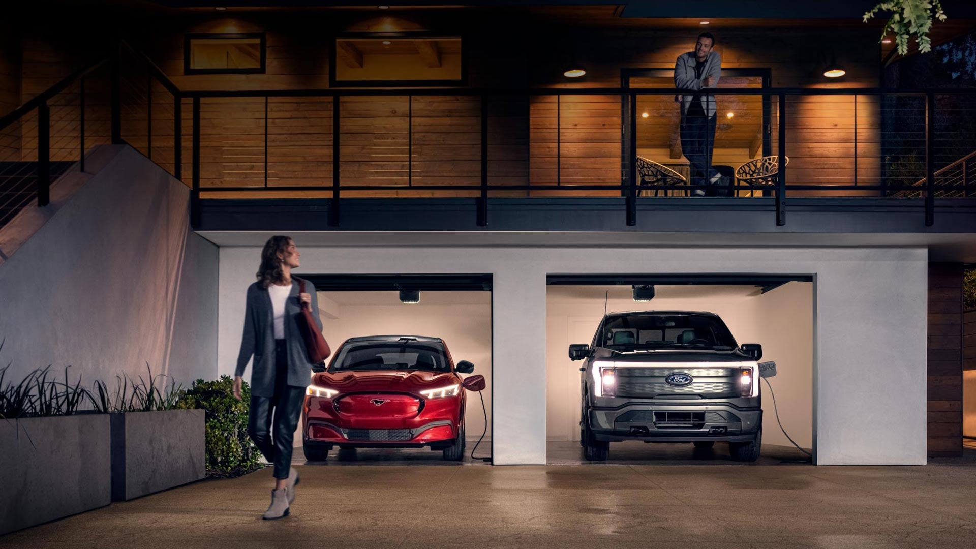 Woman walking out from home garage with a 2024 Mustang® Mach-E and Ford Lightning® truck in plugged-in and charging | Rock Hill Ford in Rock Hill SC